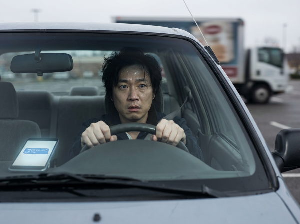 一位经历车祸创伤的男子在停车场驾车时恐慌发作，表现出恐惧和焦虑。