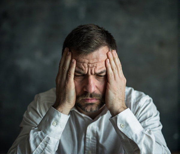 Un homme d'affaires stressé en réunion, la mine soucieuse, face à une psychologue bienveillante dans un bureau lumineux, évoquant l'anxiété sociale et la reprise de contrôle.