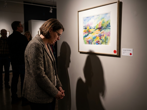 En kvinna står osäker framför sin egen utställda akvarellmålning, omgiven av skuggor som symboliserar skam och impostor-syndrom, med en 'Såld'-lapp som påminner om hennes dolda talang.